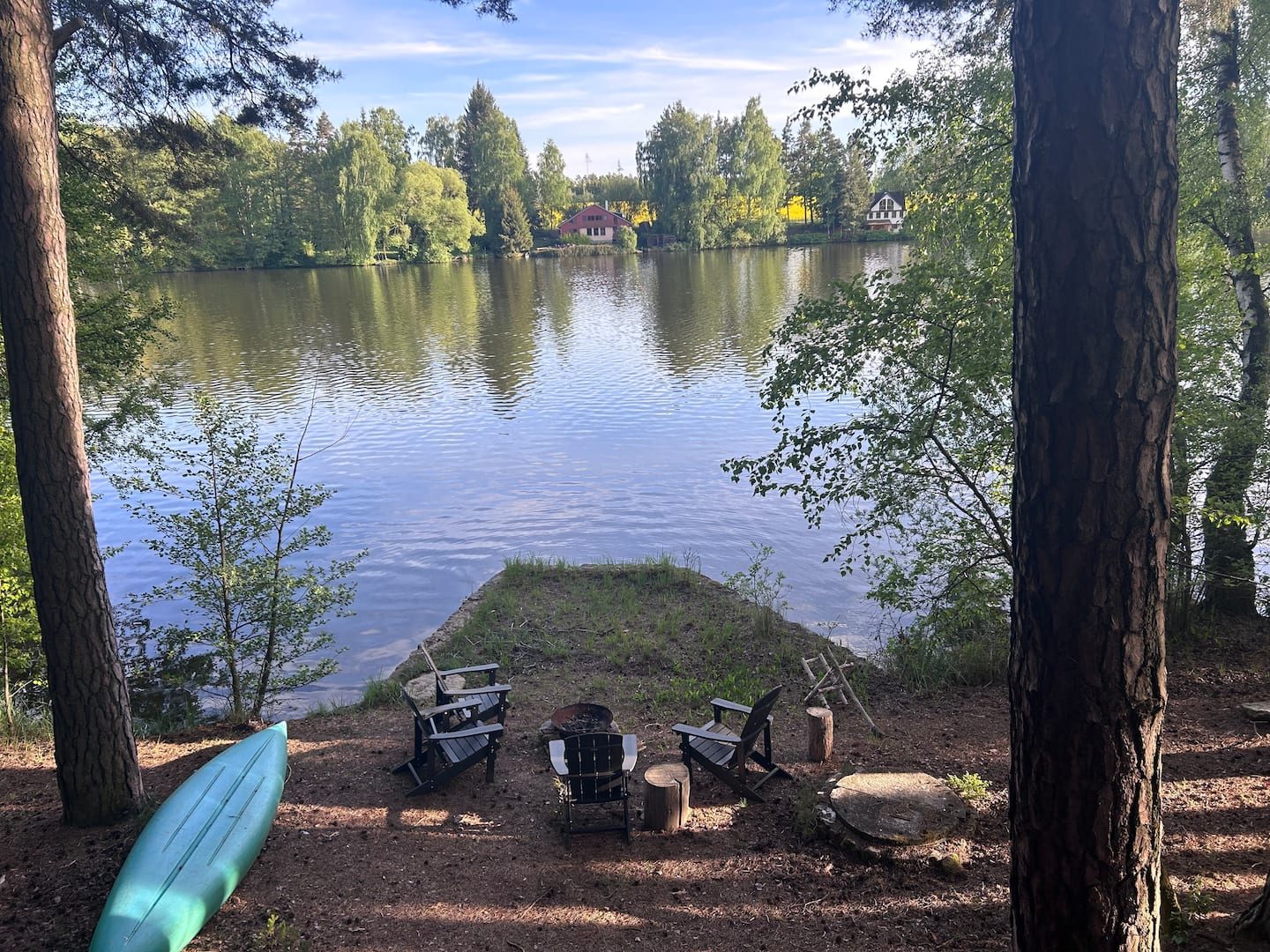 Břeh rybníka s ohništěm, křesly a paddleboardem
